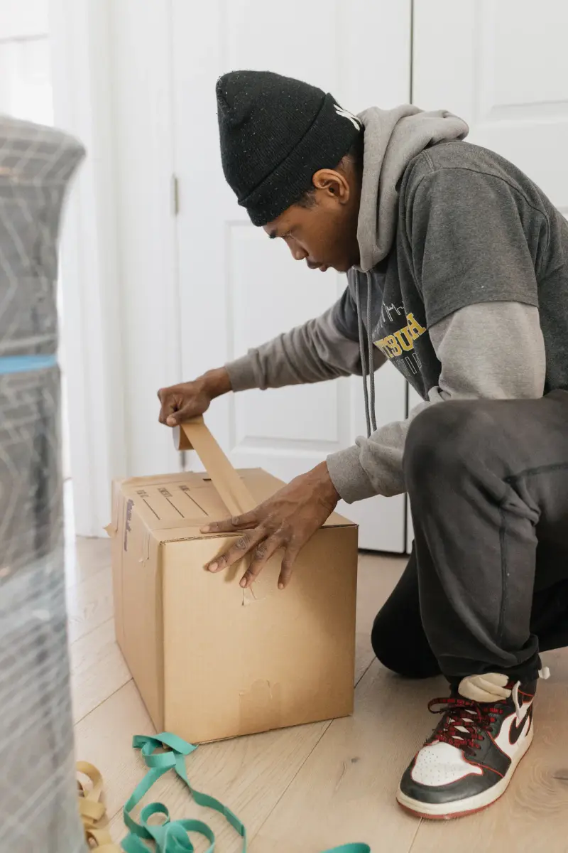 Pittsburgh Moving PGH mover taping a moving box on a wood floor next to moving straps.